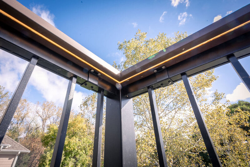 Low-angle view of aluminum deck railing with a drink rail and concealed LED lighting strip underneath. 