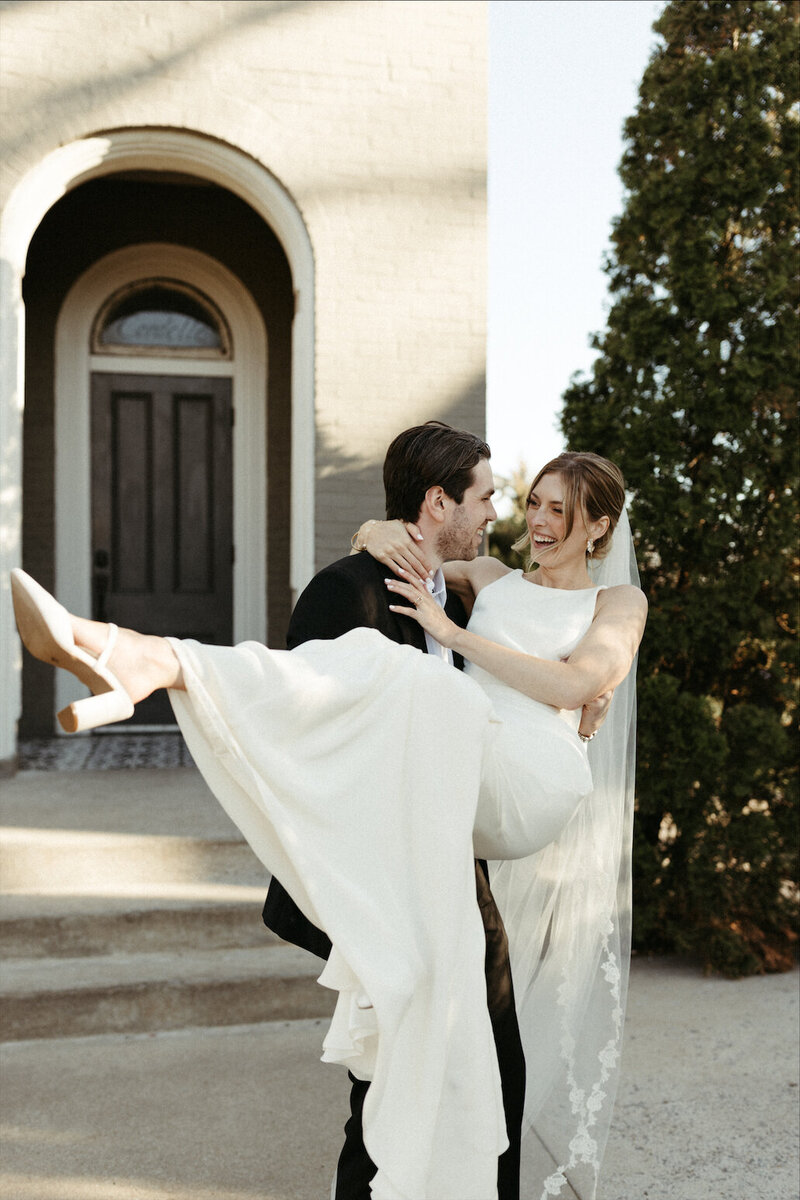 A couple standing together holding a bouquet of flowers after their wedding ceremony. 
