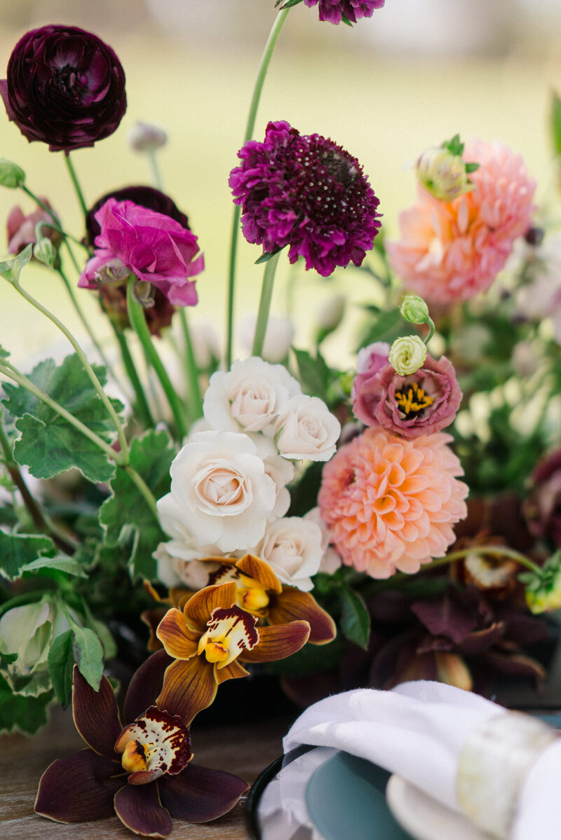 Customized table arrangement with colorful orchids for a dinner celebration.