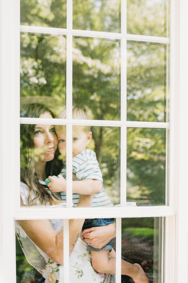 mom looking out a window holding her son