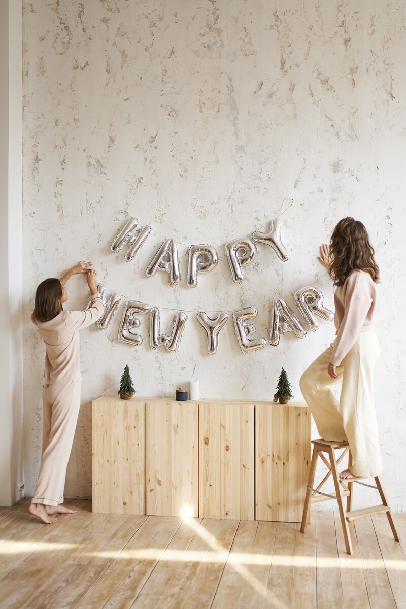 Deux femmes décorant le mur de ballons argentés pour le Nouvel An. Organisation d'événements pour particuliers