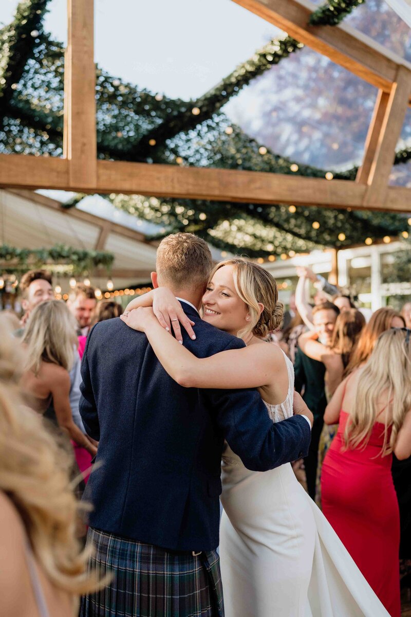 A bride and groom hug on the dancefloor of House of Elrick's wedding barnquee.
