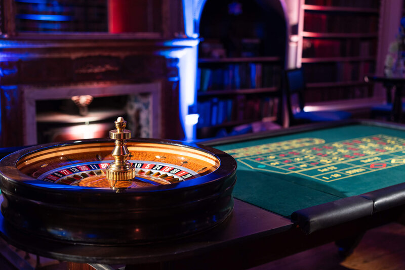 closeup of a roulette wheel at a luxury party in avington park’s library with blue party lighting across the bookshelves behind