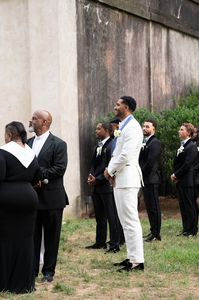 A groom stands and smiles at his bride at the Swan House in Atlanta, GA