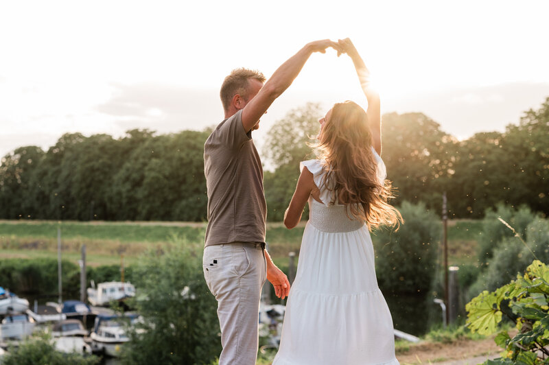 Een stel danst bij zonsondergang langs een rivier tijdens een loveshoot, vastgelegd door Monica Stout Fotografie in een romantische setting.