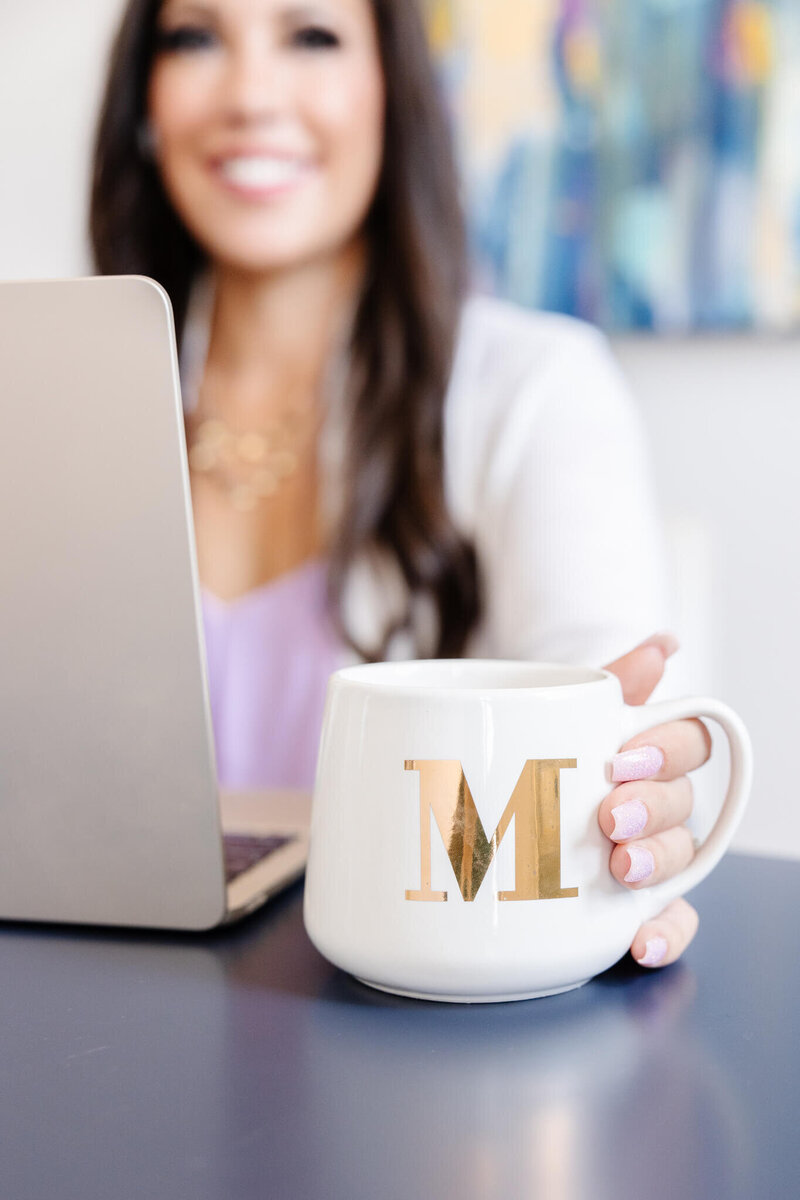 Monica Louie with a letter M mug working on Facebook and Instagram ads