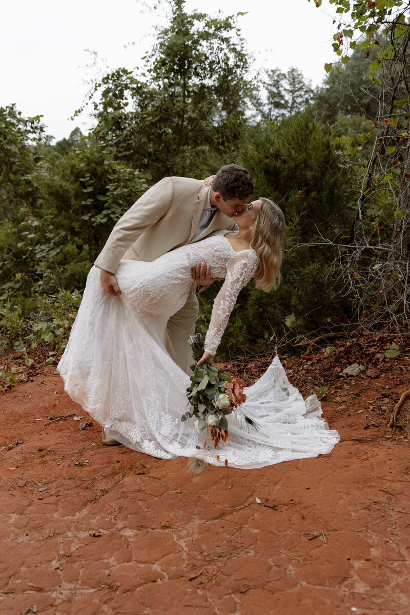Eloping couple shares a romantic dip kiss with a red rock canyon as their backdrop—capturing the ultimate elopement moment.