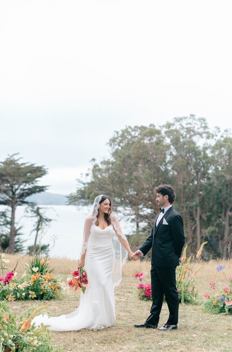 Wedding photographer in the bay area. Bride and groom holding hands on a coast.