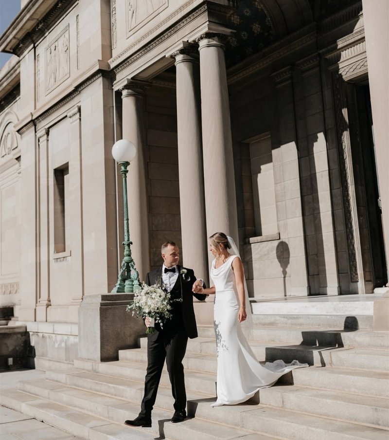 A bride and groom walking down the steps of the Memorial Art Gallery in Rochester, NY.
