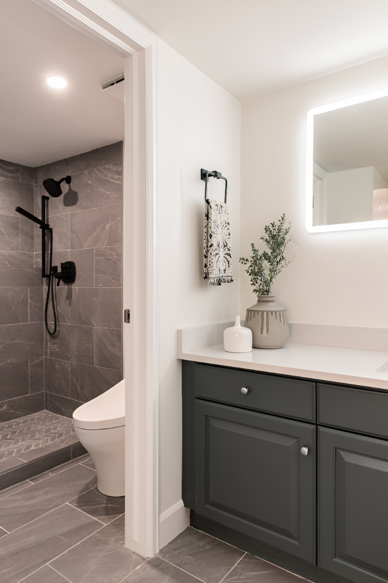 A close up shot of a moody mountain modern bathroom with grey tile, green cabinetry and moody accents by Sister Studio.