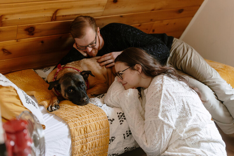couple getting cozy with their dog at a cabin engagement session in the poconos