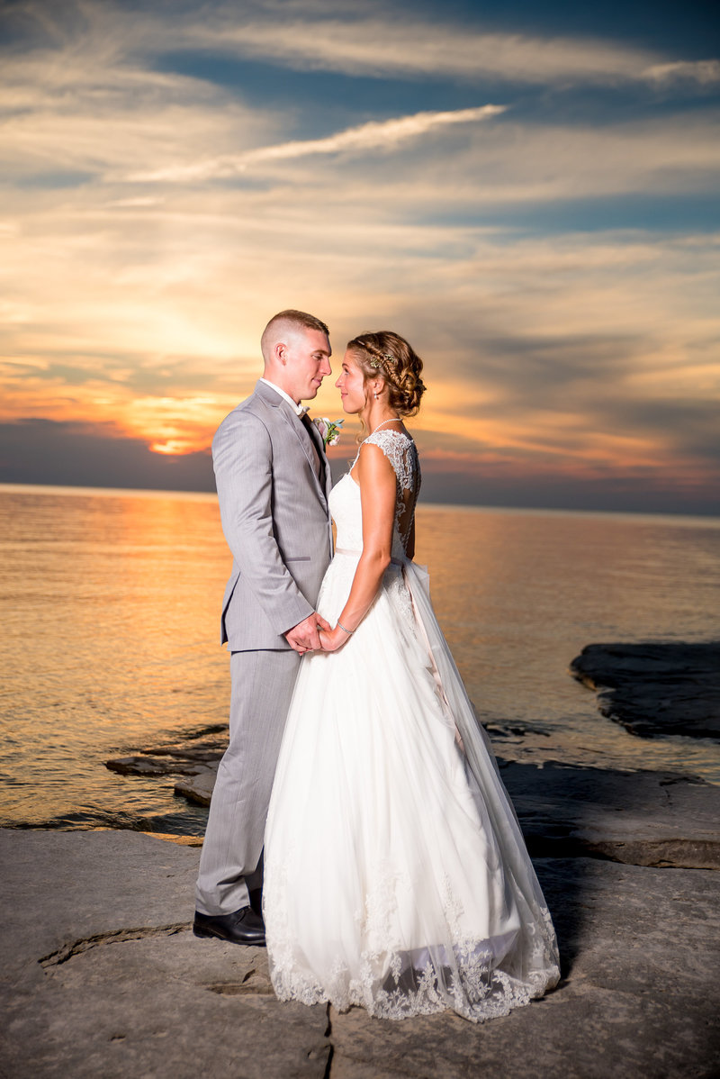 Sunset over Lake Ontario as bride and groom look at each other