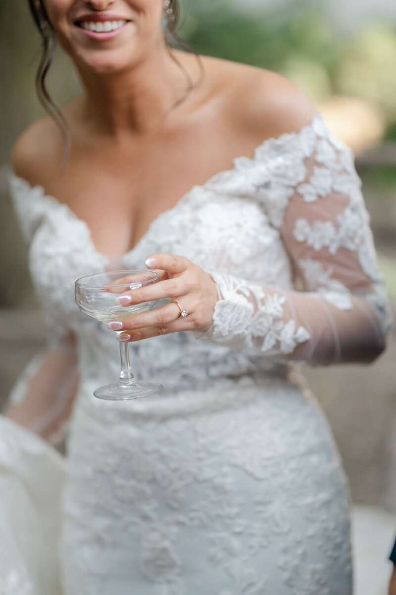 Elegant bride dressed with luxury dress drinking champagne with focus on wedding ring