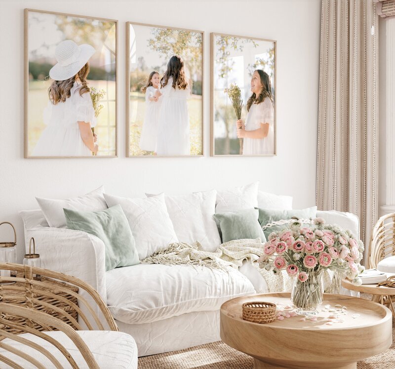 Two young sisters playing in white dresses adorns the walls of a coastal designed home complete with florals on the coffee table.