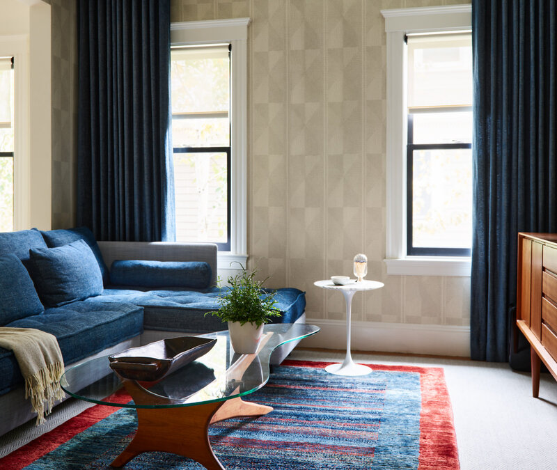 Interior designers in Boston create family room in historic Brookline home with a blue sectional, Pierre Frey bedding, Schumacher wallpaper, and custom drapery panels.