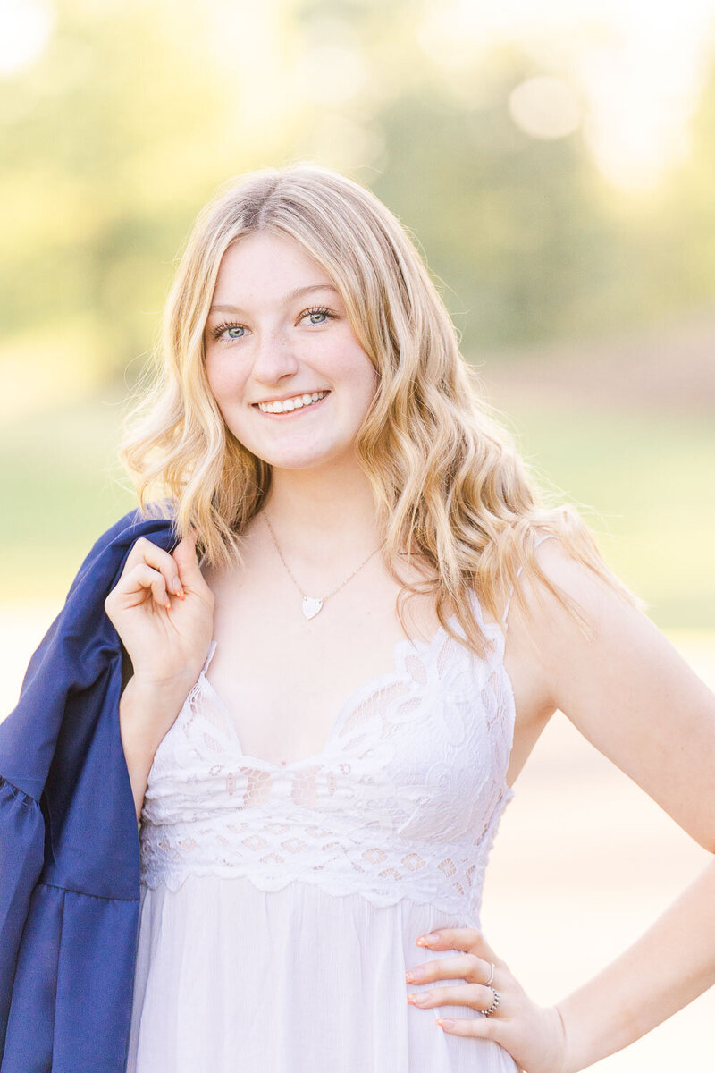 high school girl holding to her graduation gown during Ashburn, VA senior pictures