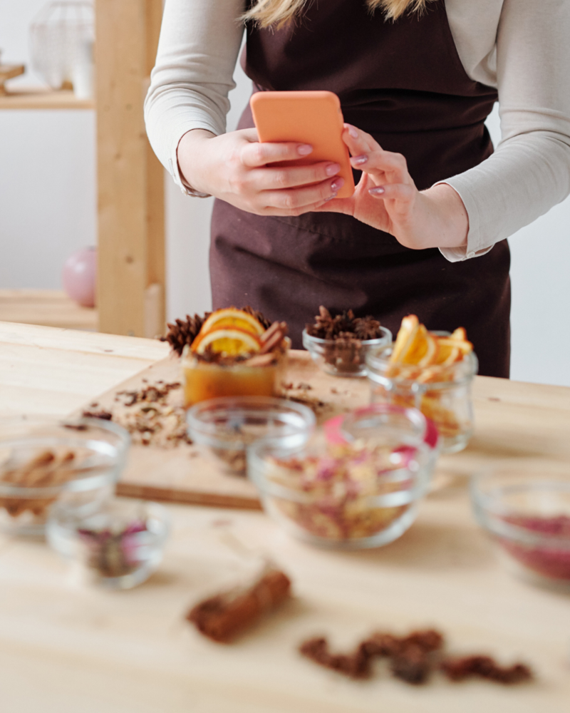 woman in apron taking a picture of ingredients with smart phone