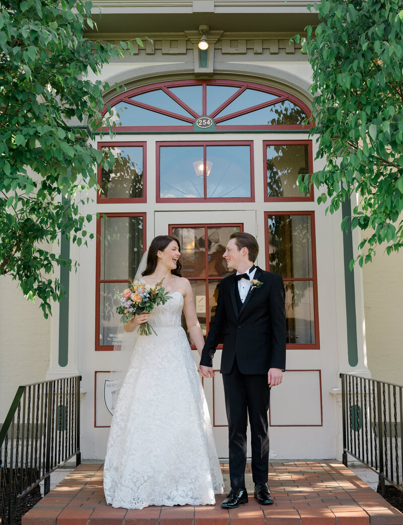A couple smile at each other on the front steps of an old Manor in Michigan