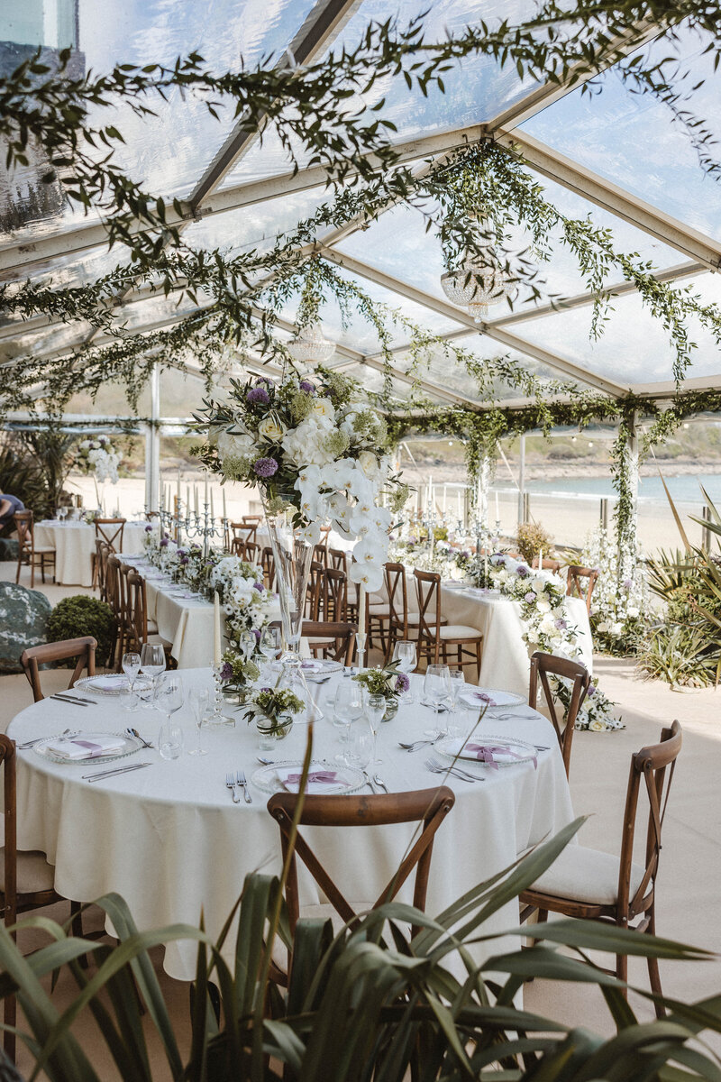A marquee at Carbis Bay with hanging foliage and tall vase arrangements on the tables 