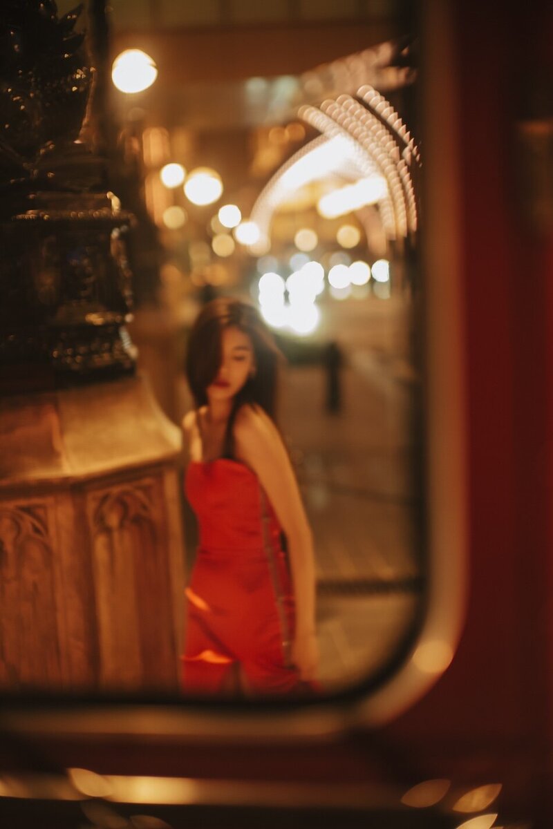 Destination couture photoshoot with a woman in. a red gown at night in the city.