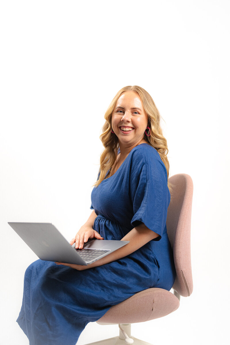 A virtual assistant sitting on a chair with a laptop