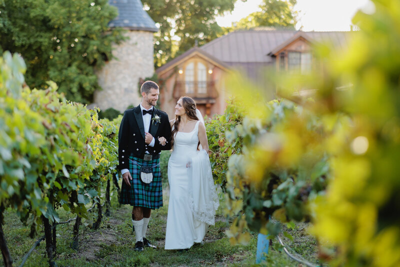 A couple walks hand in hand through the vineyard by the castle