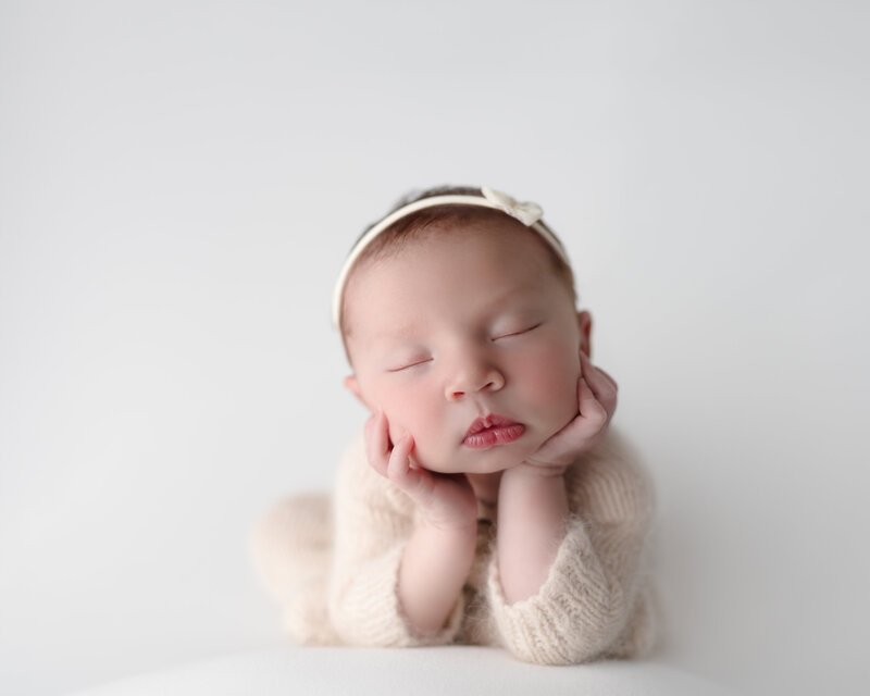Elegant and clean studio portrait of a newborn baby in the beloved froggy pose, highlighting pure simplicity.