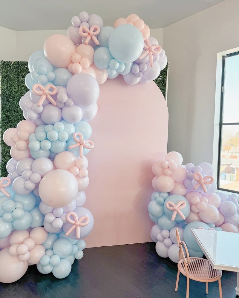 Arch backdrop with pink, purple, blue balloon garlands with balloon bows