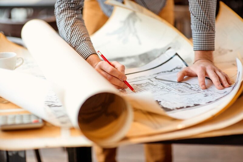 architect0sketches-on-yellowed-partially-rolled-up-plans