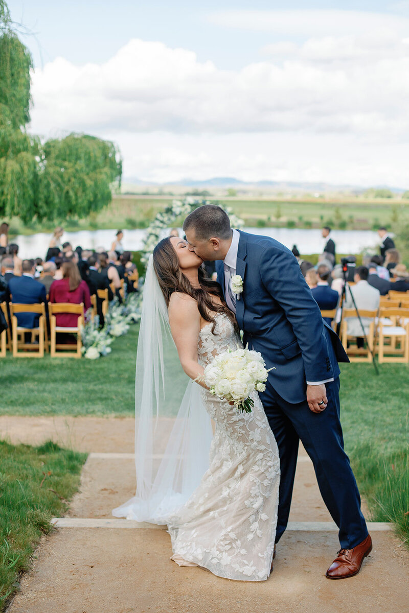 A beautiful outdoor wedding ceremony with a couple sharing a kiss.