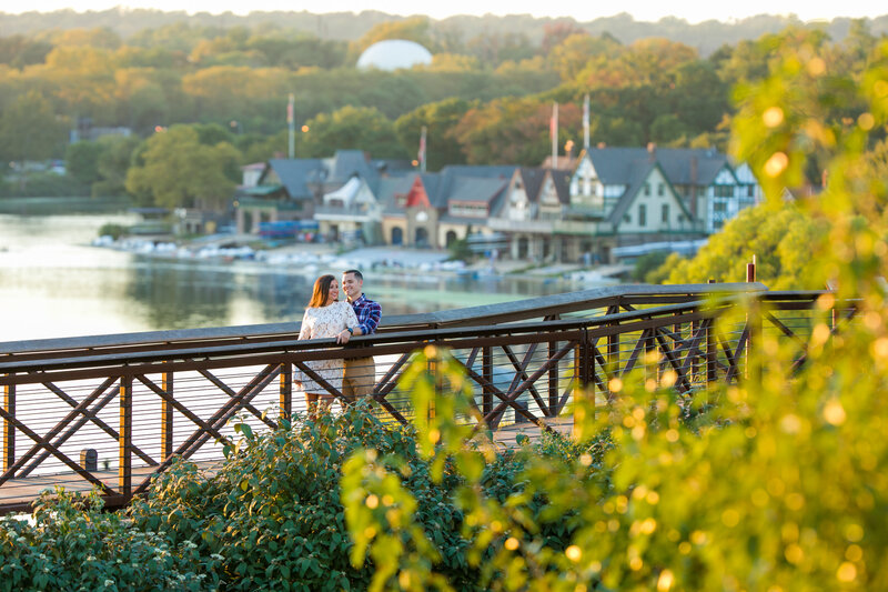Engaged couple standing with the glowing lights of Boathouse Row in the background during their engagement photo session.