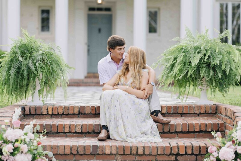 a couple looking into each other's eyes while sitting on the brick steps of a home