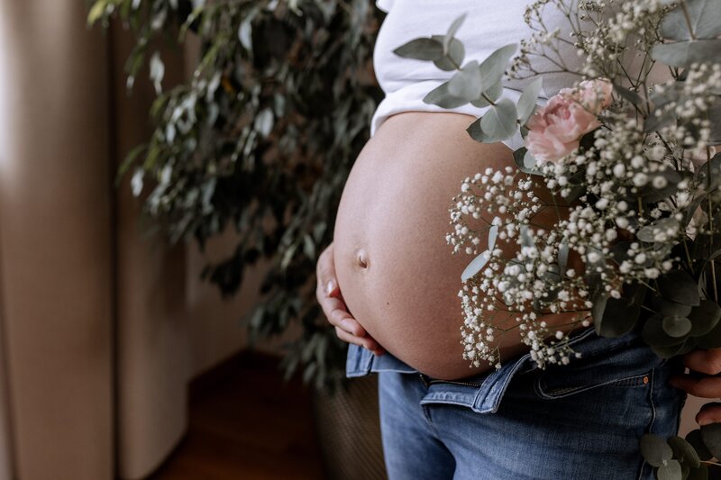 Babybauch von der Seite mit Blumen