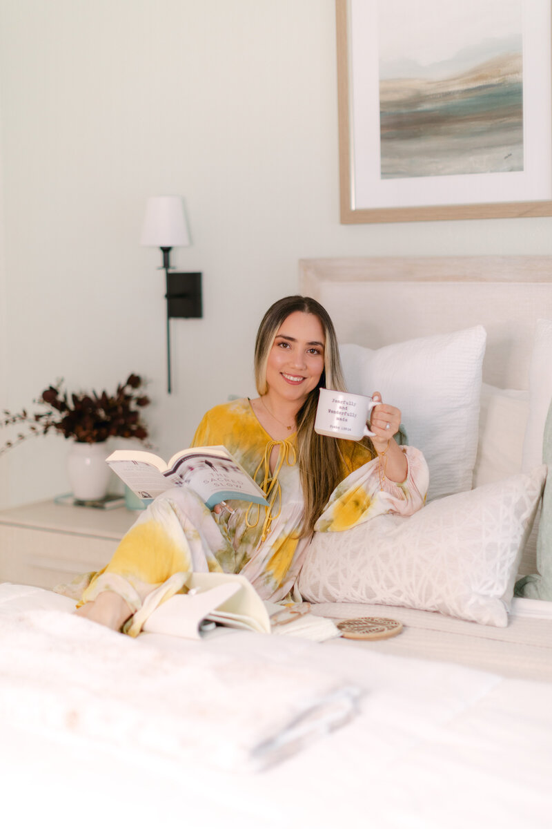 Merlyn Asencio holding a book and cup of tea, creating a warm and comforting atmosphere that reflects trauma-informed therapy values.