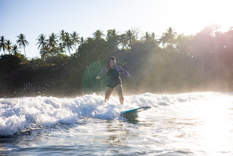 Surfer rides wave with sun setting behind