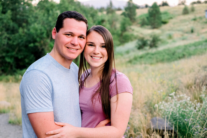 couple looking and smiling at camera while holding each other taken by spokane engagement photographer
