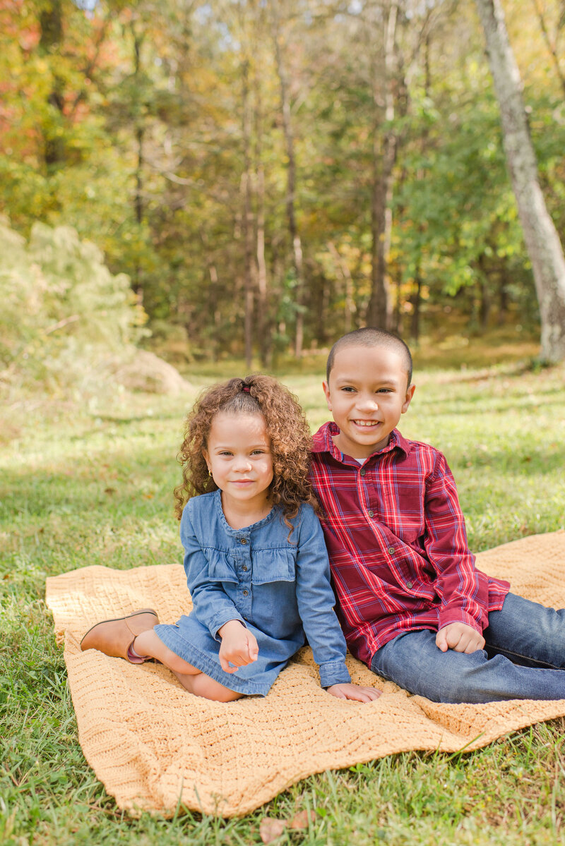 two kids sitting on a blanket in nature