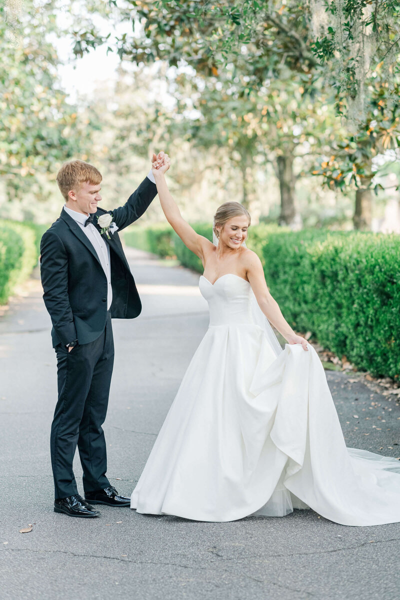 Groom hlding brides hand as she spins in her dress