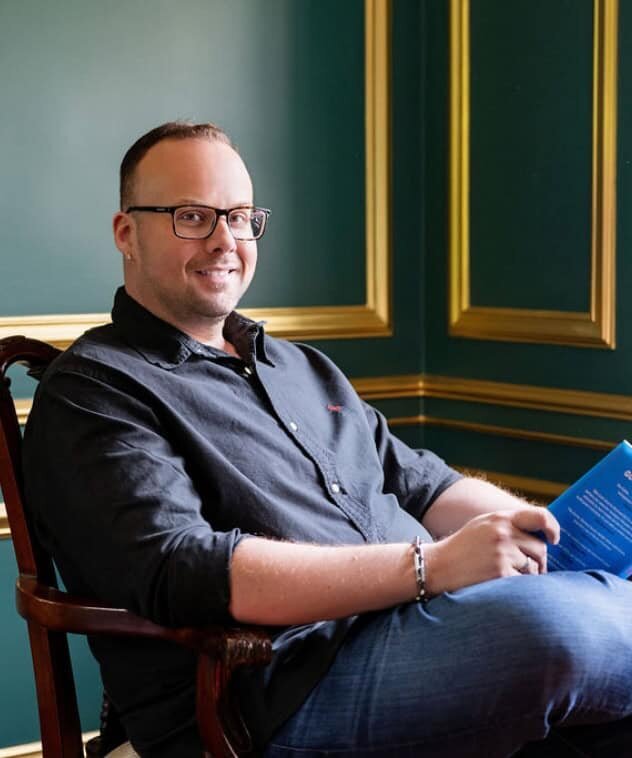 Dr. Mike provides valuable information in his free guide that will help you assess your relationship with porn, shown here sitting in a chair reading a book.