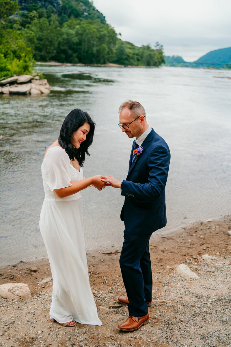 Bride and groom exchanging rings during a peaceful riverside elopement ceremony
