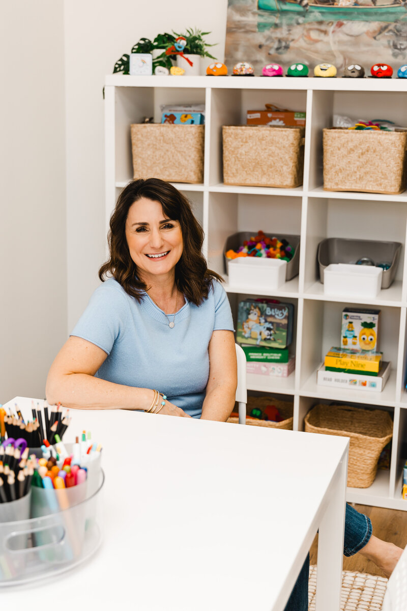 Dena smiling while sitting in the play area at her office
