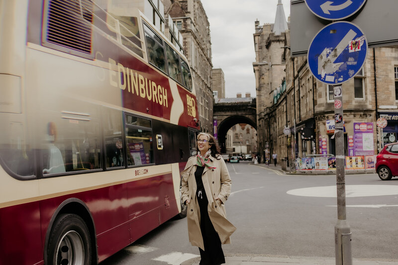 A photo of Margaret along the streets of Edinburg with a bus driving past