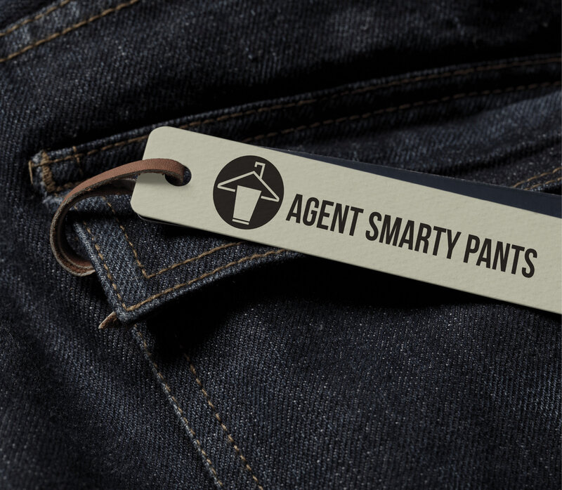 Agent Smarty Pants logo displayed on a clothing tag over dark denim, showcasing a bold and playful brand identity.