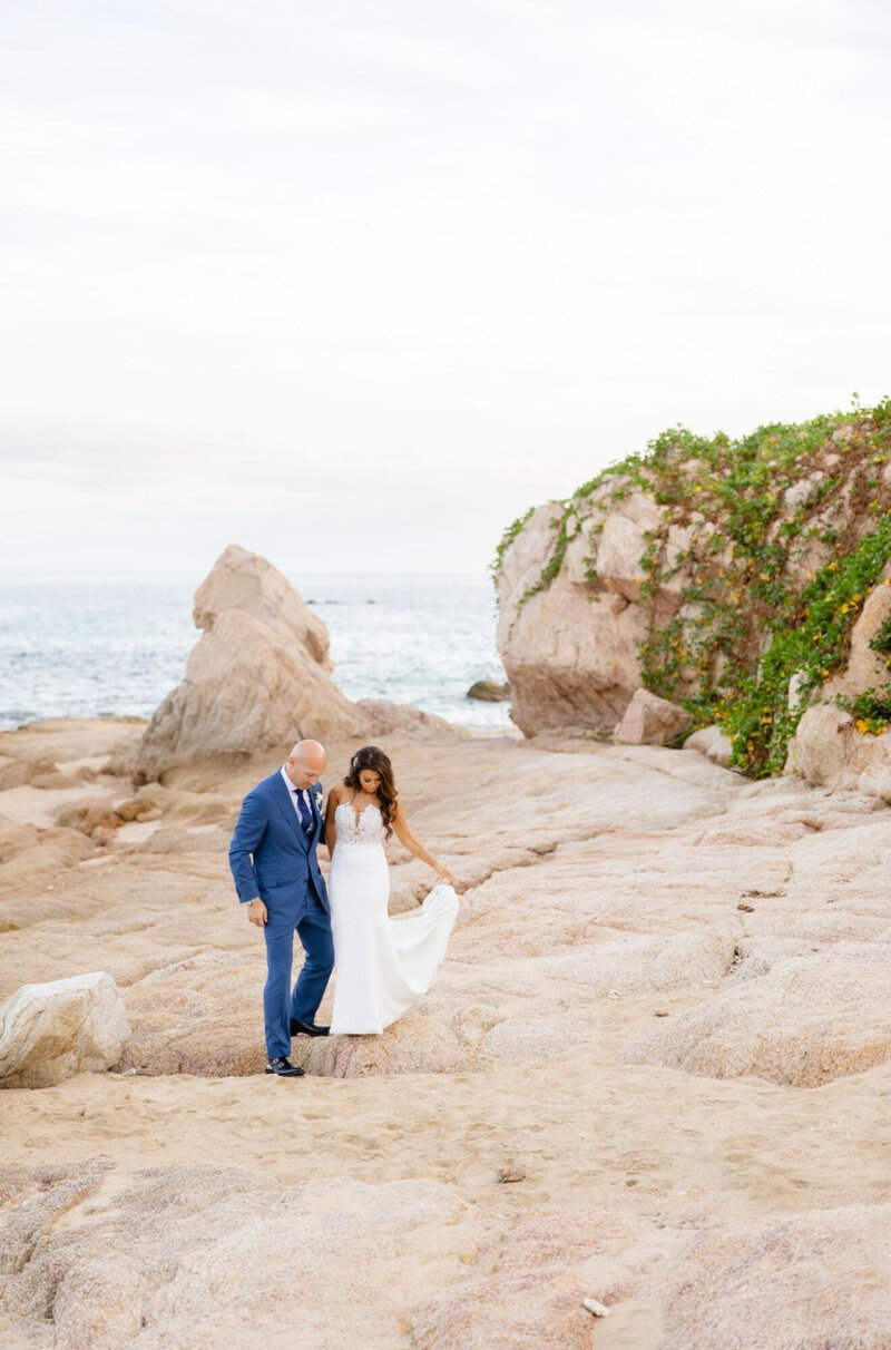 A bride and groom traverse the Puerto Vallarta cliffs with the ocean in the background
