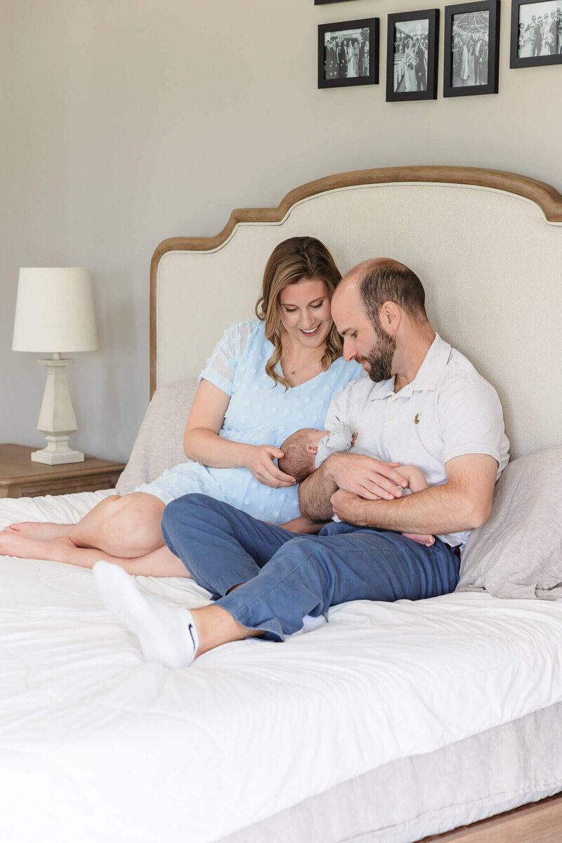 A couple snuggling their newborn baby boy in bed in their Leesburg home.