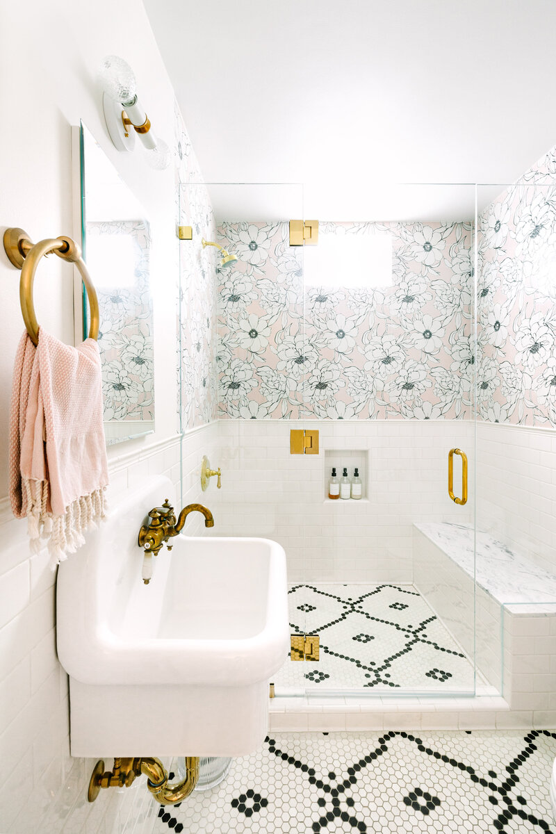 Small space bathroom with wall sink, Walker Zanger floral porcelain tile shower, frameless shower glass, and black and white Restoration Tile floor.