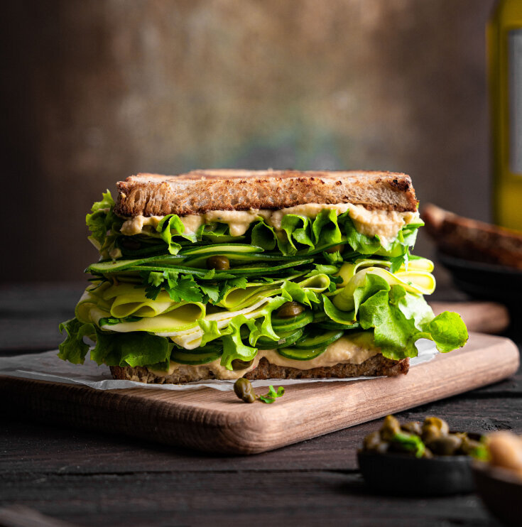 An image of a delicious looking sandwich with lettuce, greens and cheese