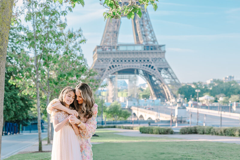 Mother with her arms wrapped around her daughter in front of the Eiffel Tower at Trocadéro during a Paris mother-daughter photoshoot.