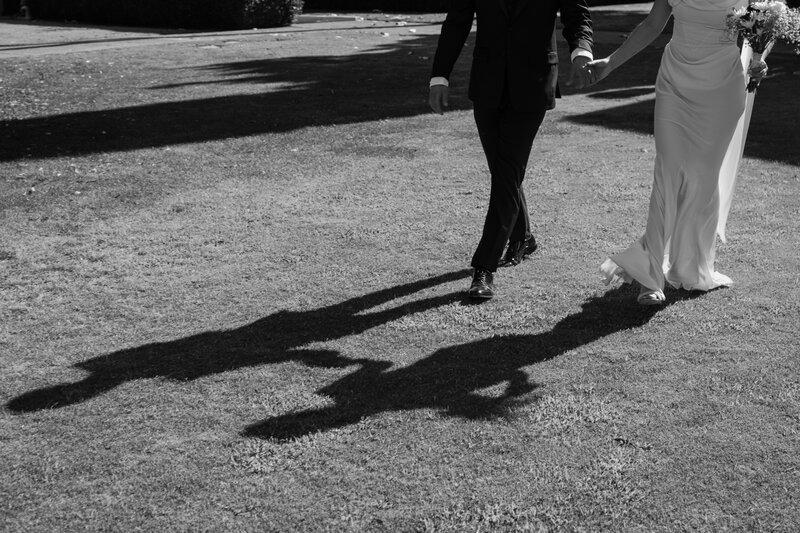 Bride and groom running together, in black and white.