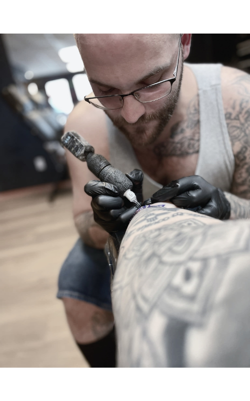 Tattoo artist at Dark Art Collective Tattoo Studio in Tacoma, WA, creating a custom black and grey tattoo